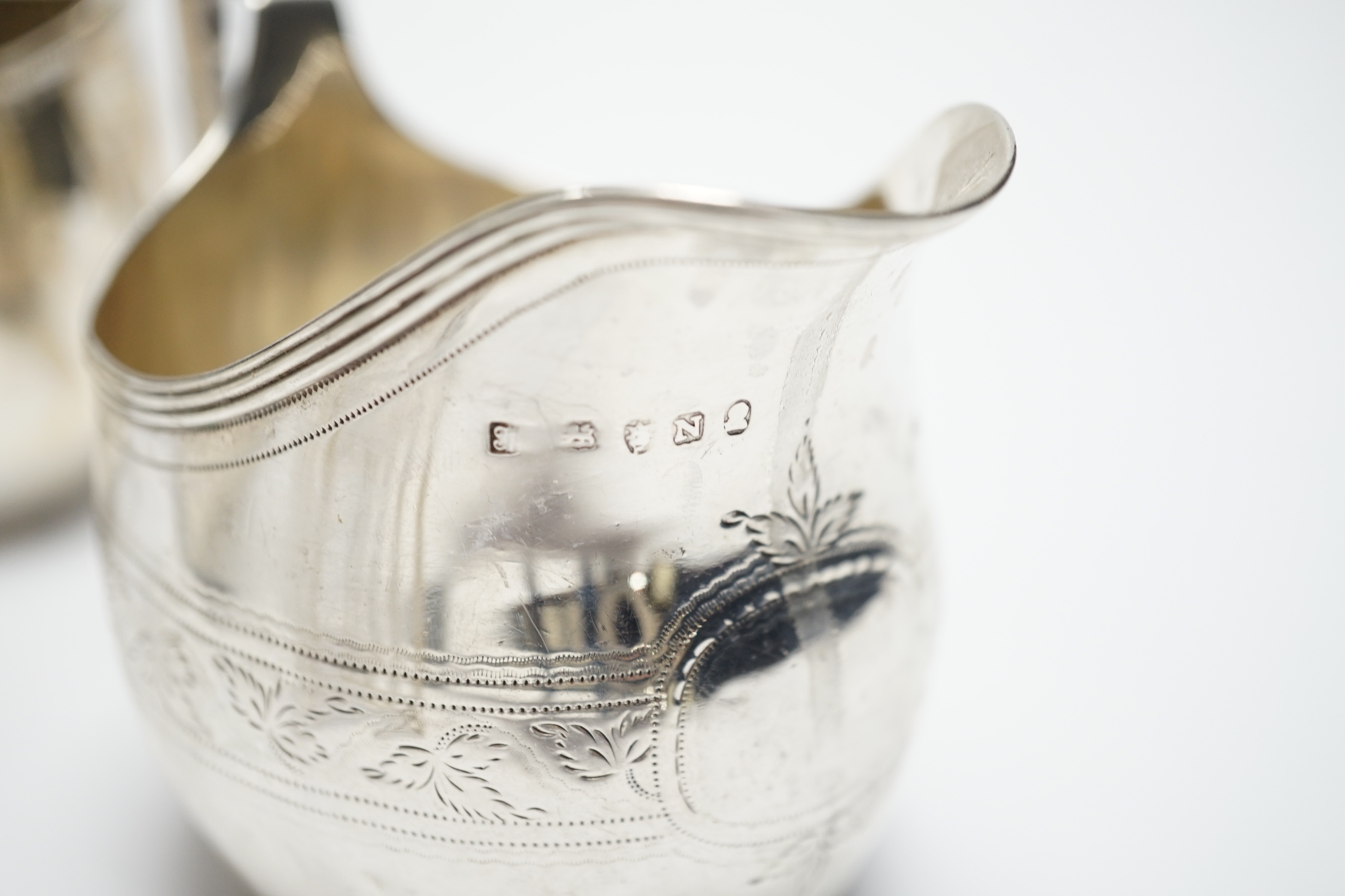 A George III engraved silver cream jug, London, 1808, height 82m, a George V silver cream jug and matching sugar bowl, and a George V silver five bar toast rack, 15.4oz.